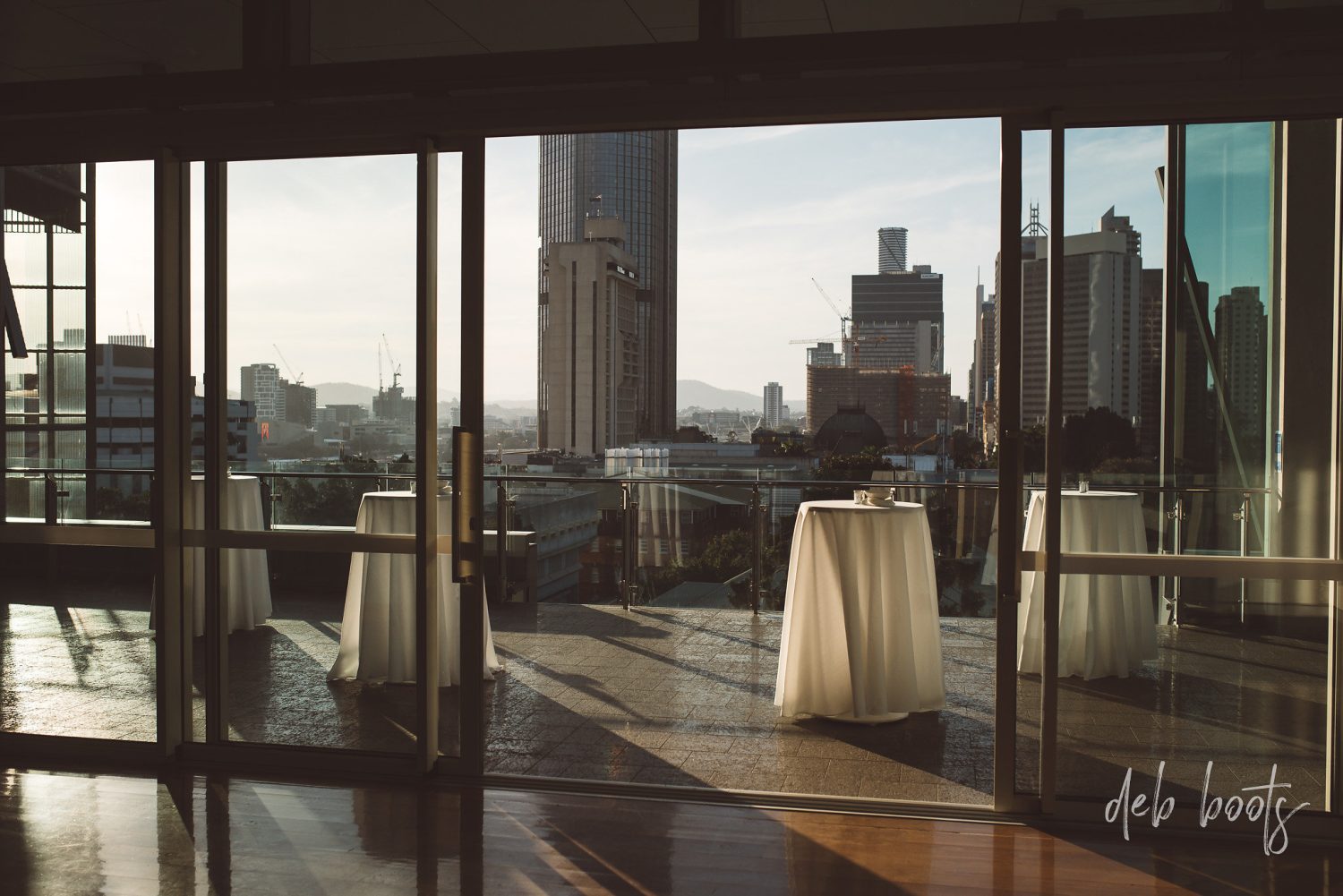 Room Three Sixty terrace at golden hour with cocktail tables and the Brisbane CBD beyond
